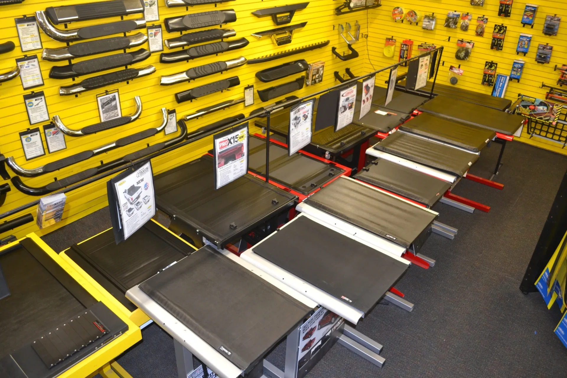 An assortment of treadmills on display in a fitness equipment store with yellow walls lined with accessories.