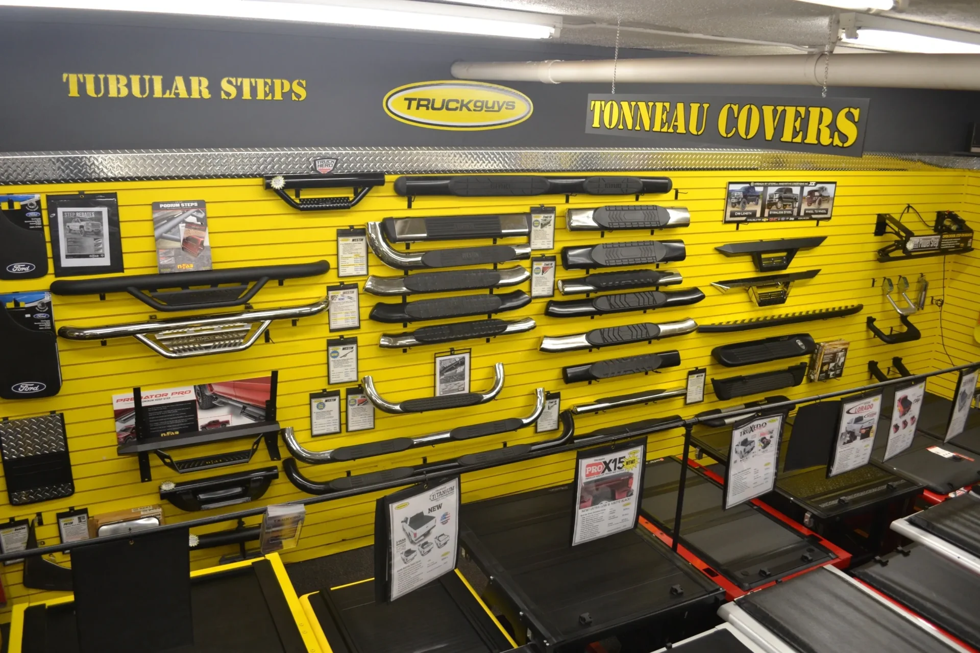 A display of various truck accessories including tubular steps and tonneau covers in a retail setting.