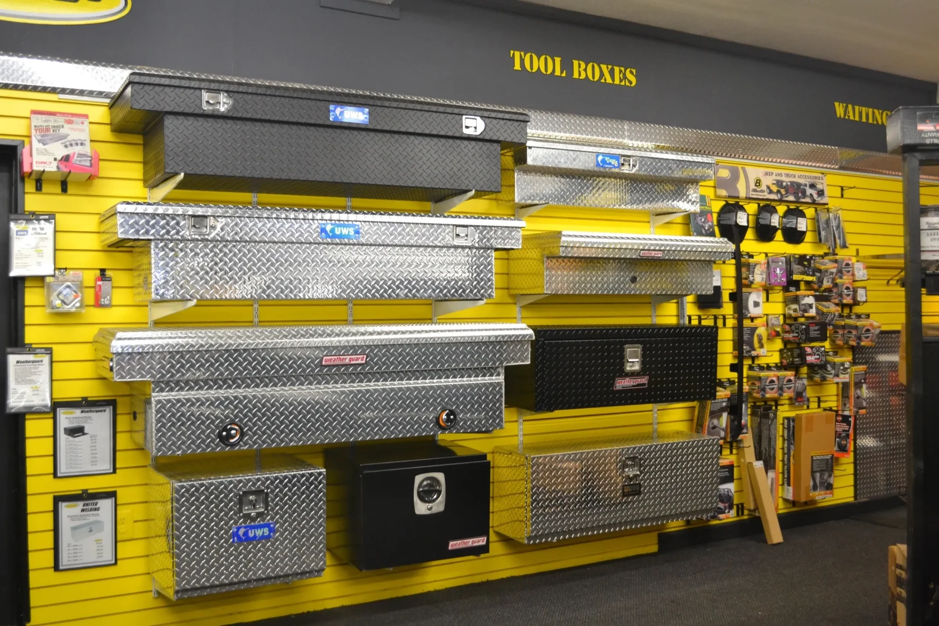 A display of various metal tool boxes for sale on the wall of a hardware store.