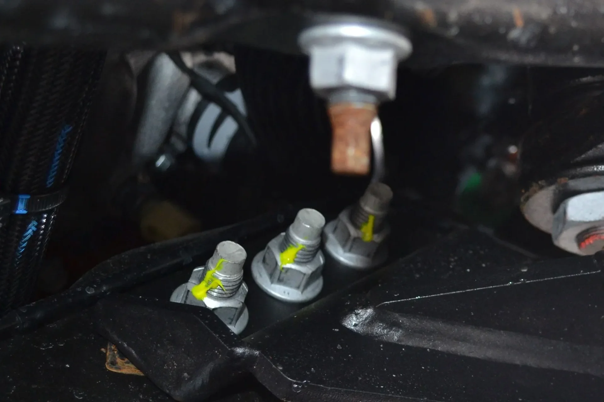 Close-up of automotive spark plugs and ignition components under a vehicle's hood.