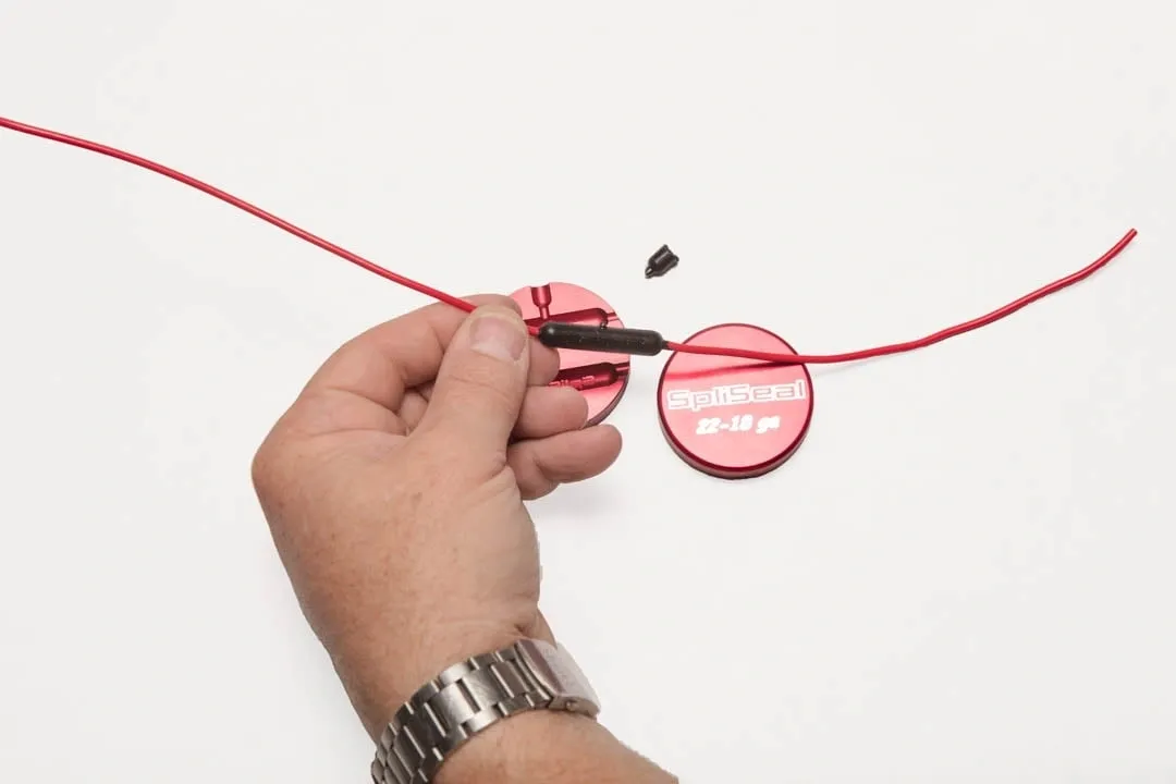 A person cutting a red plastic security seal with wire cutters.