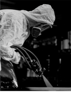 Picture of a person spraying a material into the back of a truck bed.